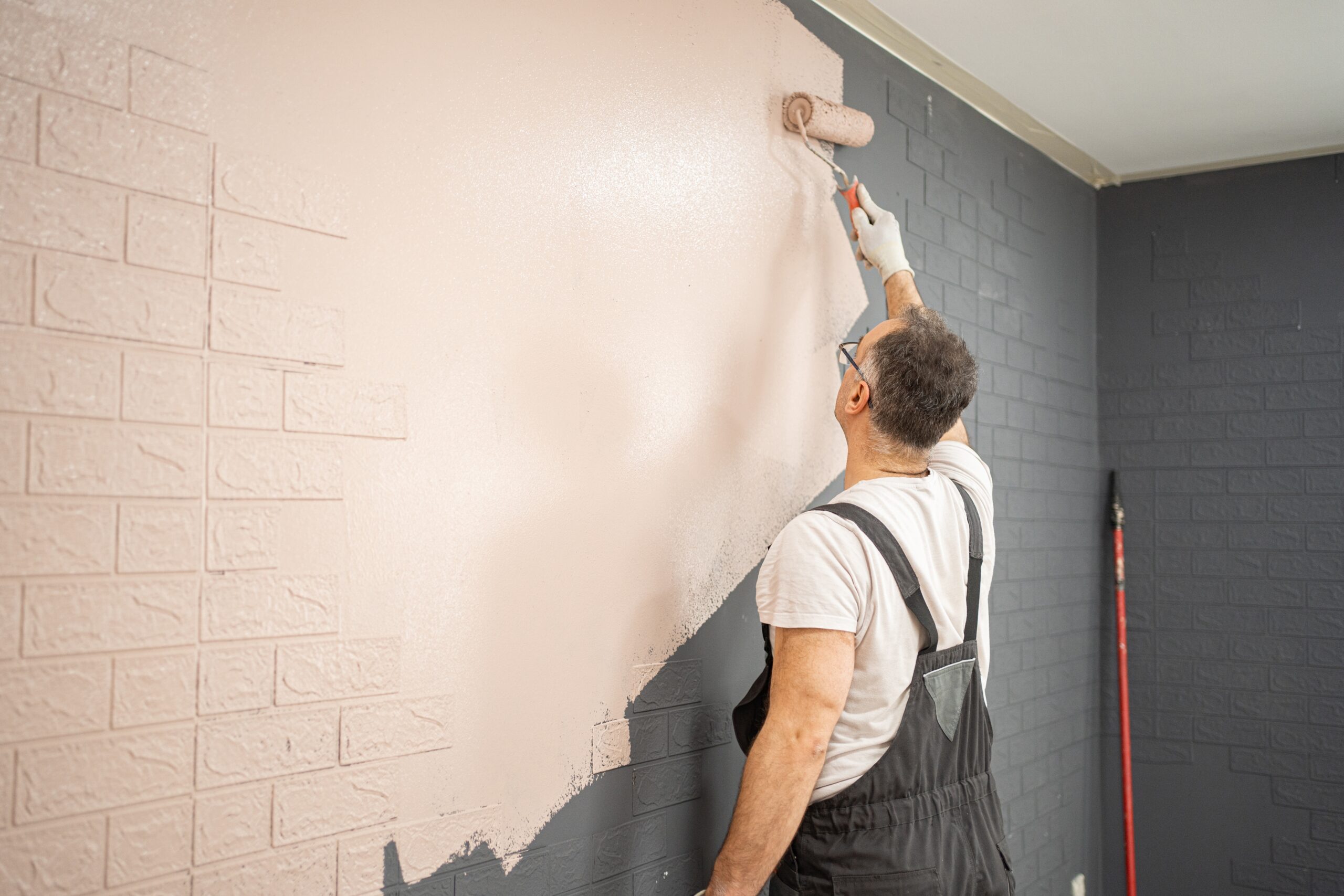 Man,Painting,Brick,Wall,With,Paint,Roller