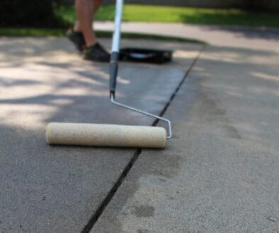 Low,Angle,View,Of,Person,Sealing,Driveway,With,Acrylic,Based